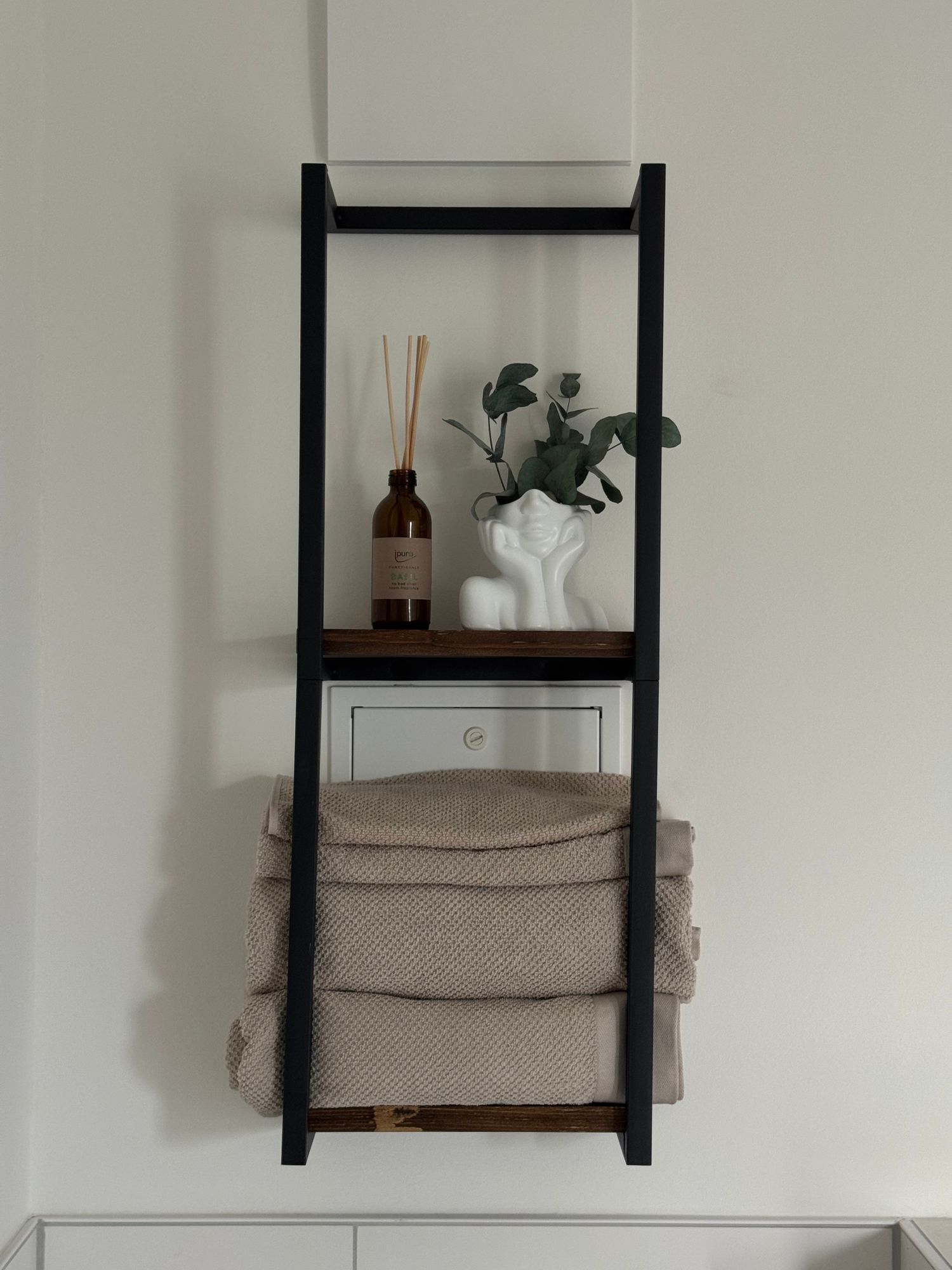 Wall-mounted bathroom shelf holding towels