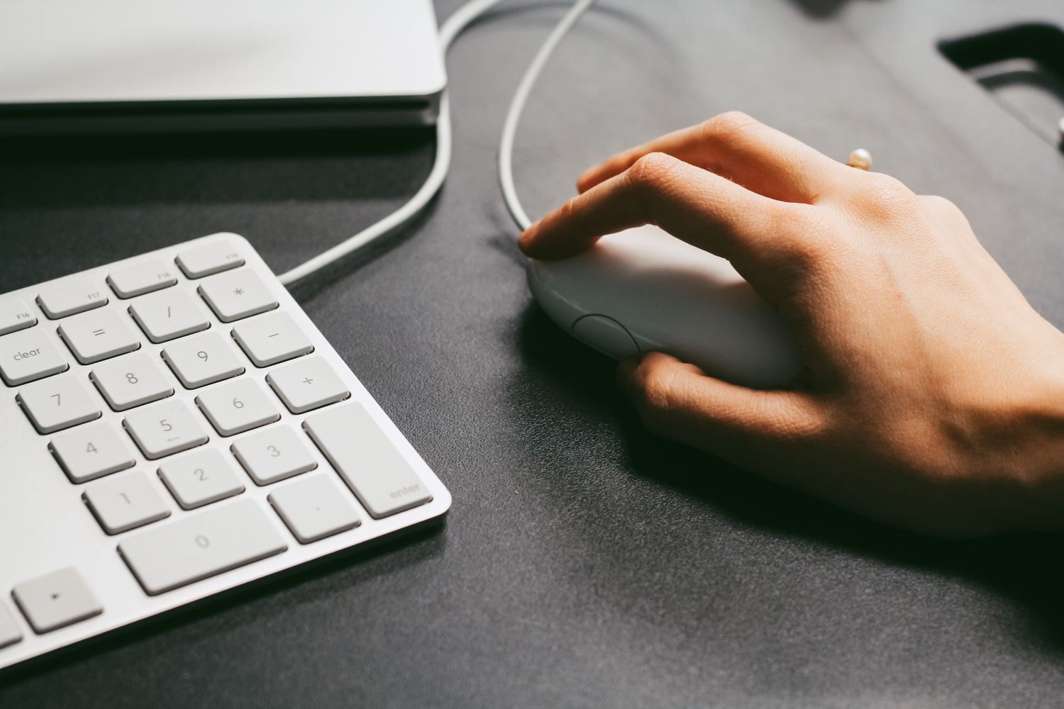 Hand bedient eine Computermaus neben einer Tastatur
